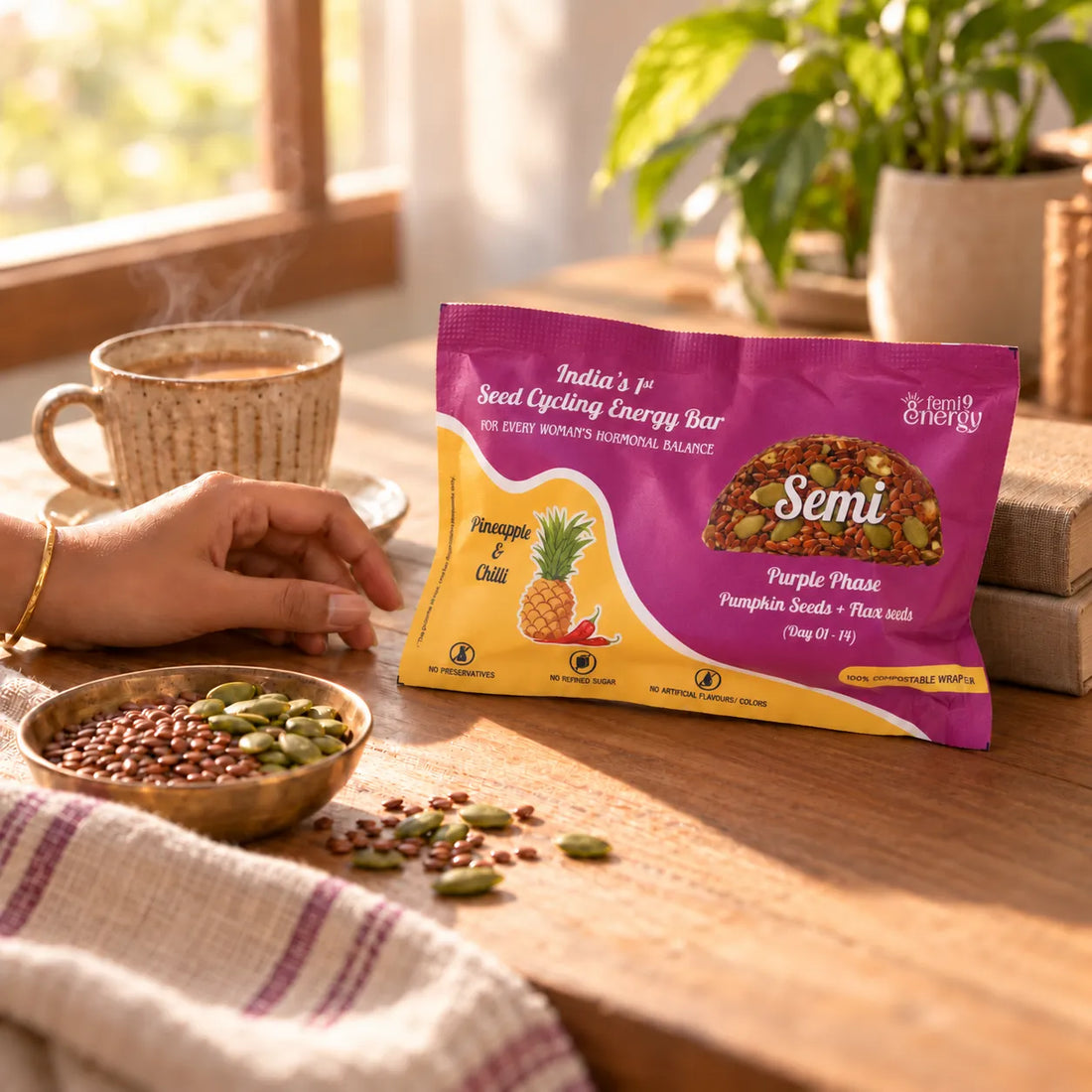 A hand reaching for a Purple Semi Pineapple & Chilli bar beside a cup of masala chai