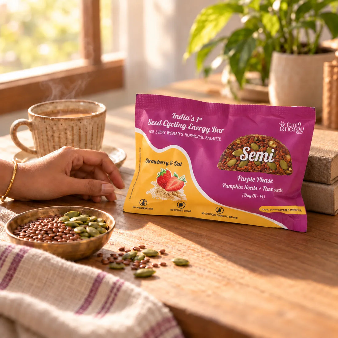 A hand reaching for a Purple Semi Strawberry & Oat bar beside a cup of masala chai